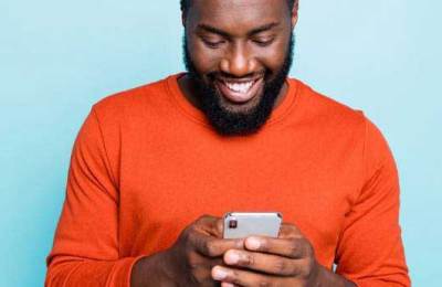 Man in orange sweater smiles while using ICC's Incoterms 2020 app